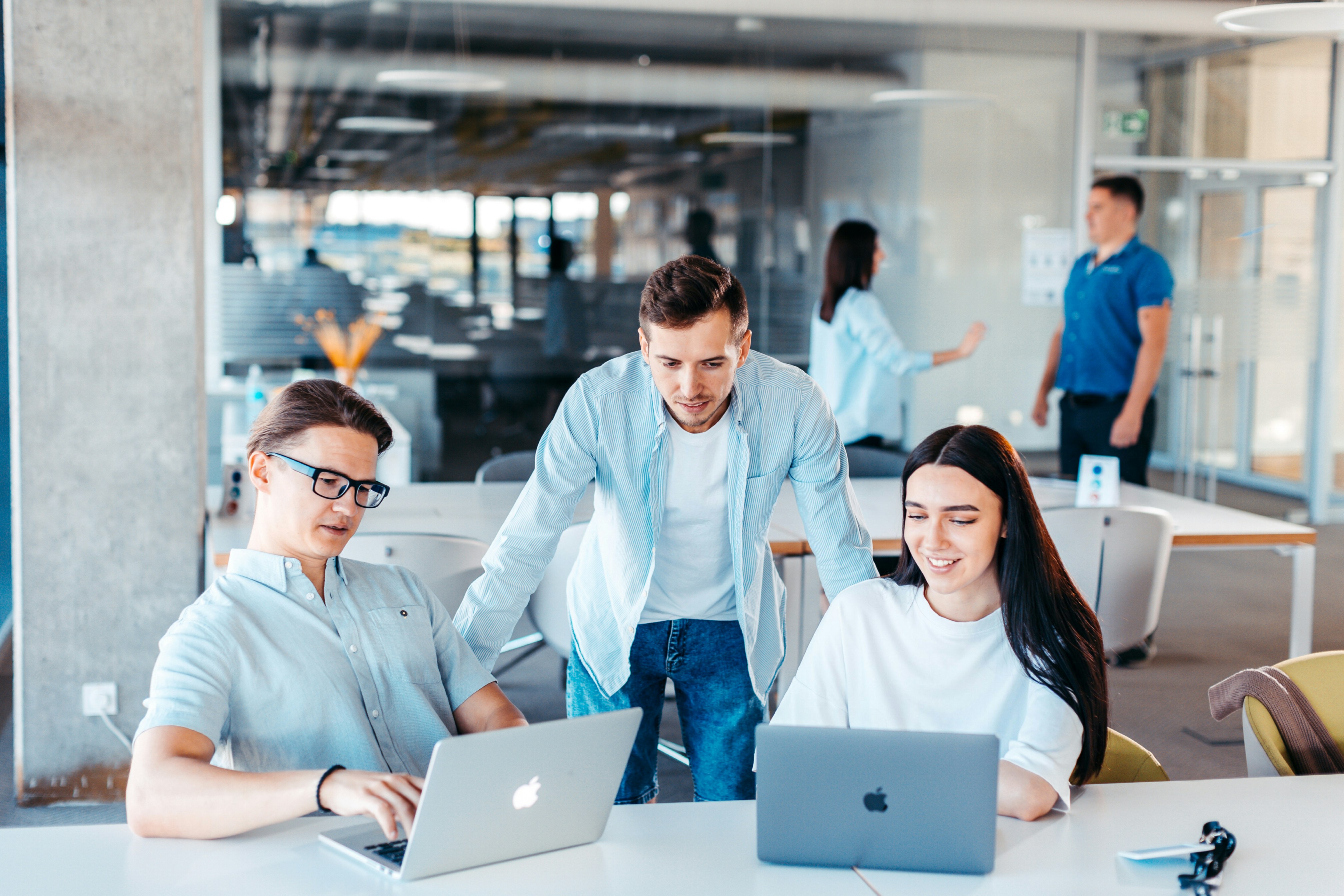 Enterprise software development team working together in a modern open-plan office environment with laptops and multiple screens