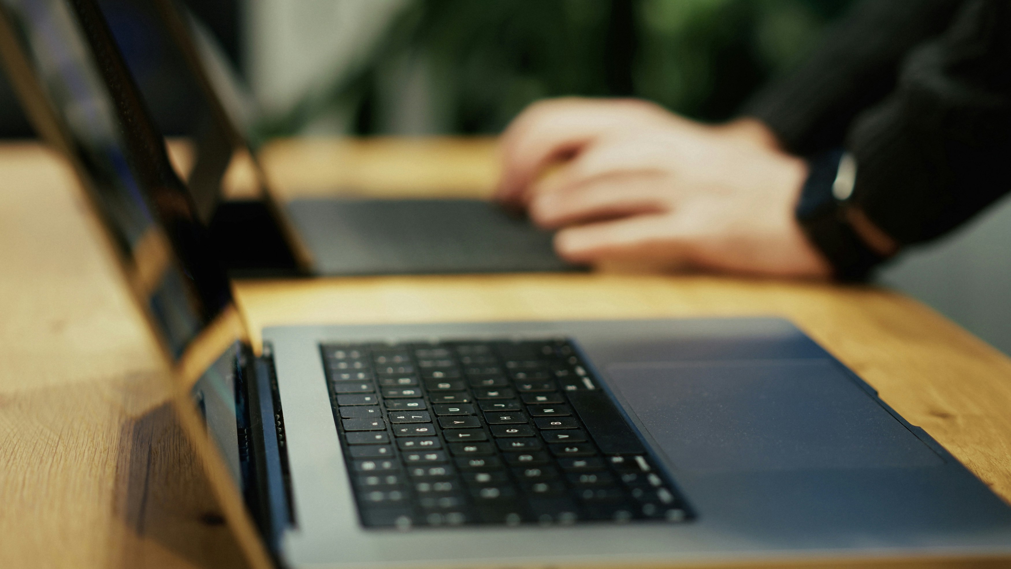 Developer working on enterprise software application on a laptop at a wooden desk in a focused development environment